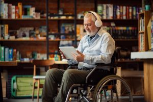 An older adult with a tablet and headphones diving into a lesson for a new skill.