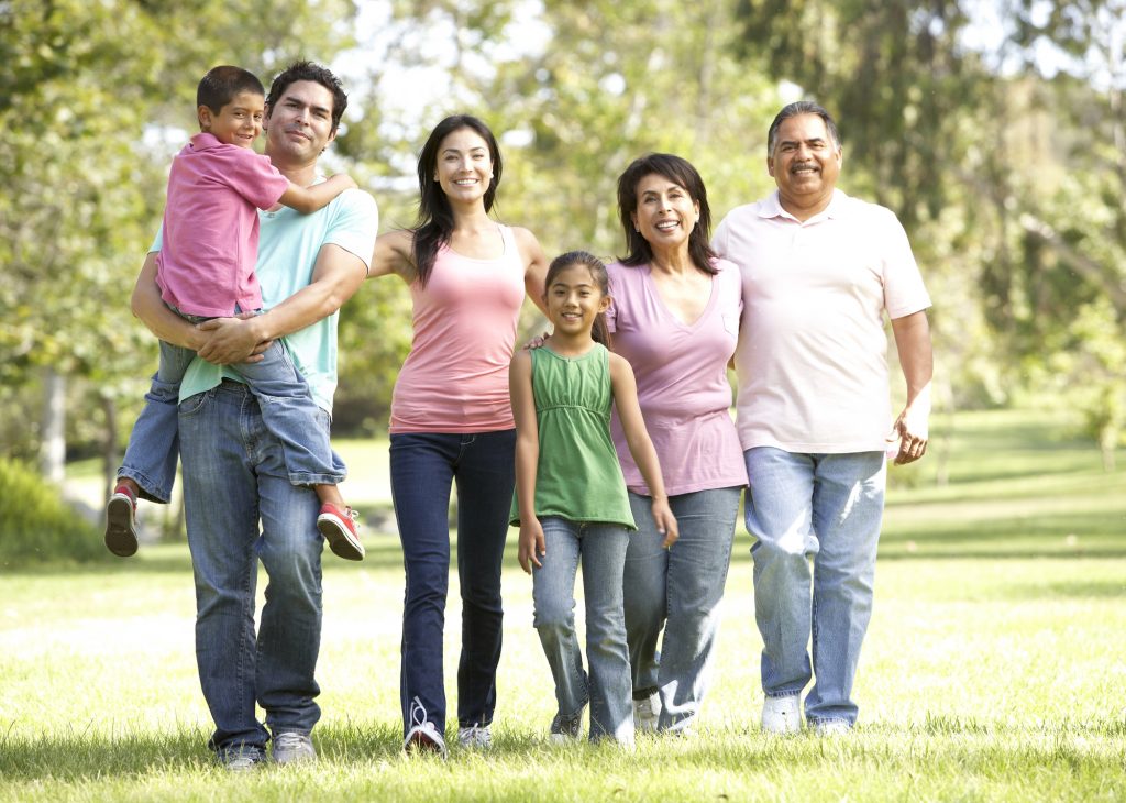 Three generations of a family enjoying a walk in the park on a sunny day.