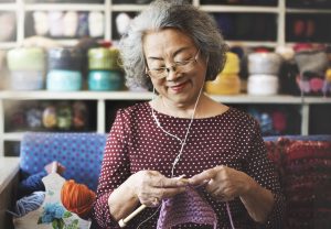 A retired adult knitting as a hobby-turned-business endeavor.