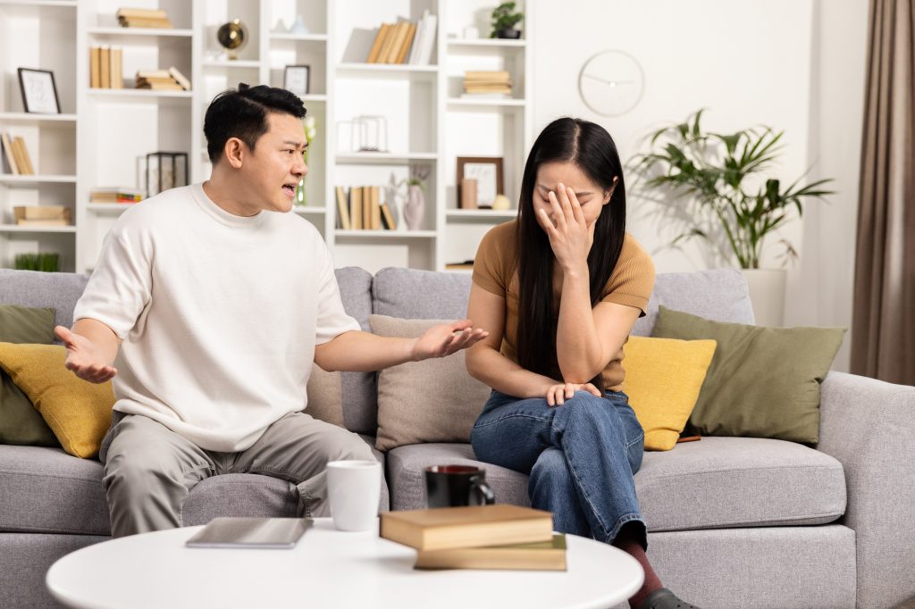 A couple sitting on a couch having a stressful argument.